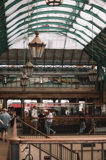 A multi-storey brick building with a ground-floor red sandstone facade displaying the sign 'COVENT GARDEN STATION' beneath large arched windows with white framing. Above, there are five additional flo